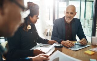 Team-Meeting in einem modernen Büro, Fokus auf einen lächelnden Geschäftsmann – Ein Bild, das Zusammenarbeit und strategische Planung in der Geschäftsentwicklung betont.