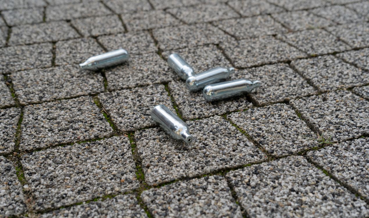Co2 Kapseln liegen auf Pflaster nach Softair Nutzung im Freien