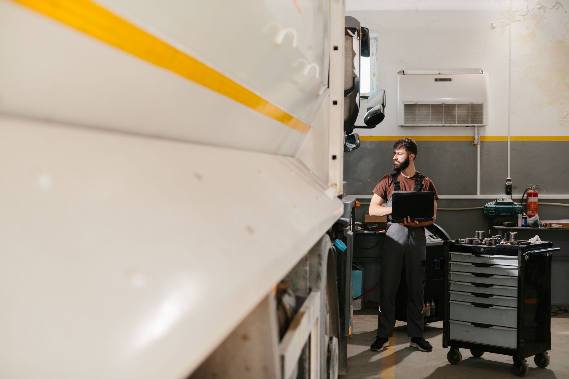 Techniker mit Laptop überprüft Lkw-Beleuchtung in Werkstatt