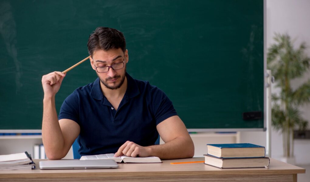 Lehrer sitzt am Schreibtisch und bereitet Unterricht vor, um Lerninhalte mit einem Erklaervideo erstellen lassen Konzept besser zu vermitteln