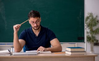 Lehrer sitzt am Schreibtisch und bereitet Unterricht vor, um Lerninhalte mit einem Erklaervideo erstellen lassen Konzept besser zu vermitteln