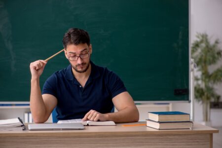 Lehrer sitzt am Schreibtisch und bereitet Unterricht vor, um Lerninhalte mit einem Erklaervideo erstellen lassen Konzept besser zu vermitteln